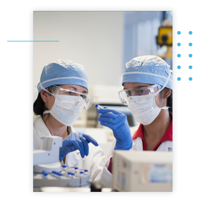Two scientists dressed in protective gear examine a sample.