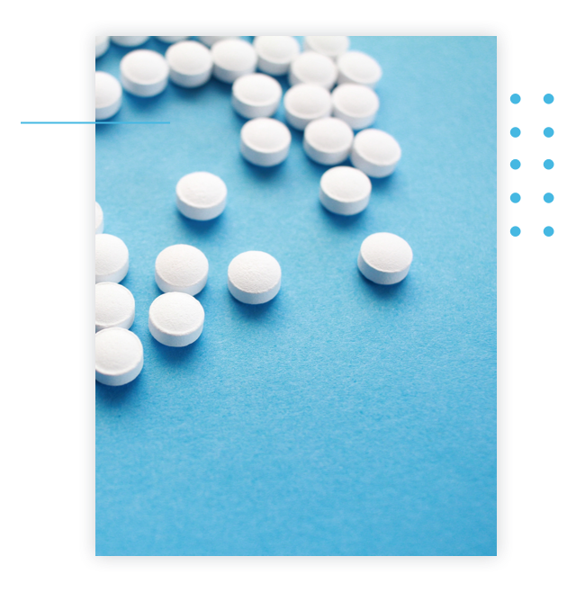 Unlabeled circular medicine tablets scattered on a table.
