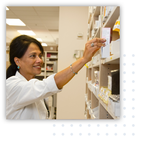 A pharmacist reaching for medicine from the pharmacy shelf.