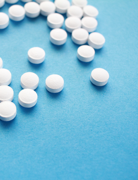 Unlabeled circular medicine tablets scattered on a table.