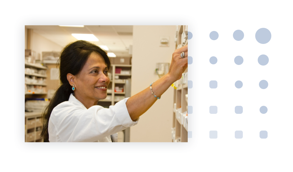 A pharmacist reaching for medicine from the pharmacy shelf.